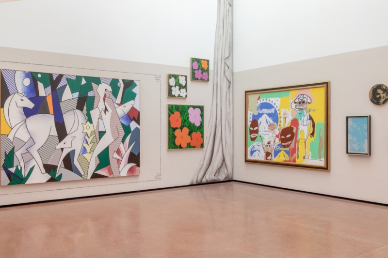 Kunstgalerie mit bunten Gemälden, darunter stilisierte Tiere, Blumen und Pop-Art-Elemente an den Wänden.