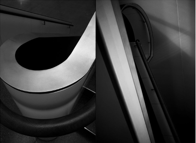Zweiteilige Schwarz-Weiß-Fotografie mit abstrakter, architektonischer Wirkung. Links im Bild ist ein geschwungener Handlauf einer Treppe zu sehen, der ein ovales, fast skulpturales Element bildet. Rechts zeigt das Bild eine steil aufragende Treppenstruktur mit dramatischen Licht- und Schattenverläufen, die die geometrische Form und Tiefe betonen. Die Aufnahme spielt mit Perspektive, Licht und Materialität und lässt die architektonischen Details beinahe wie moderne Skulpturen erscheinen.