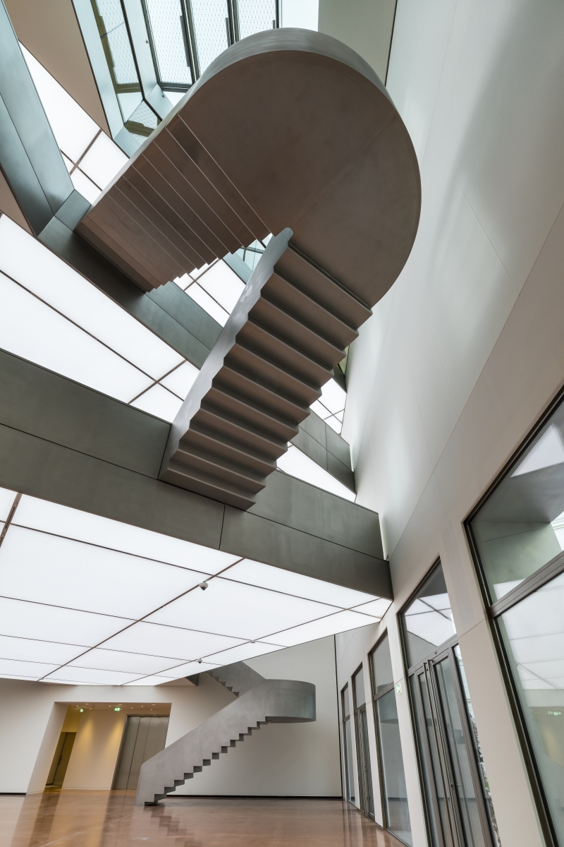 Schwebende Treppe in modernem Innenraum mit großen Fenstern und hellem Licht.
