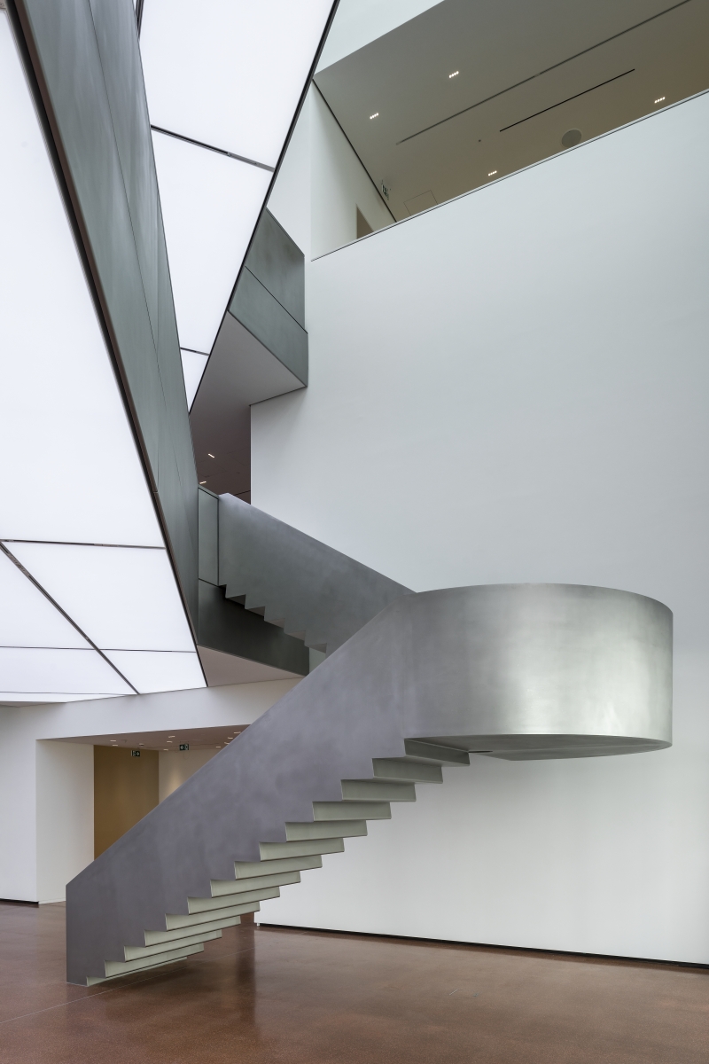 Schwebende, moderne Betontreppe in einem hellen, minimalistischen Raum mit weißen Wänden und sanfter Beleuchtung.