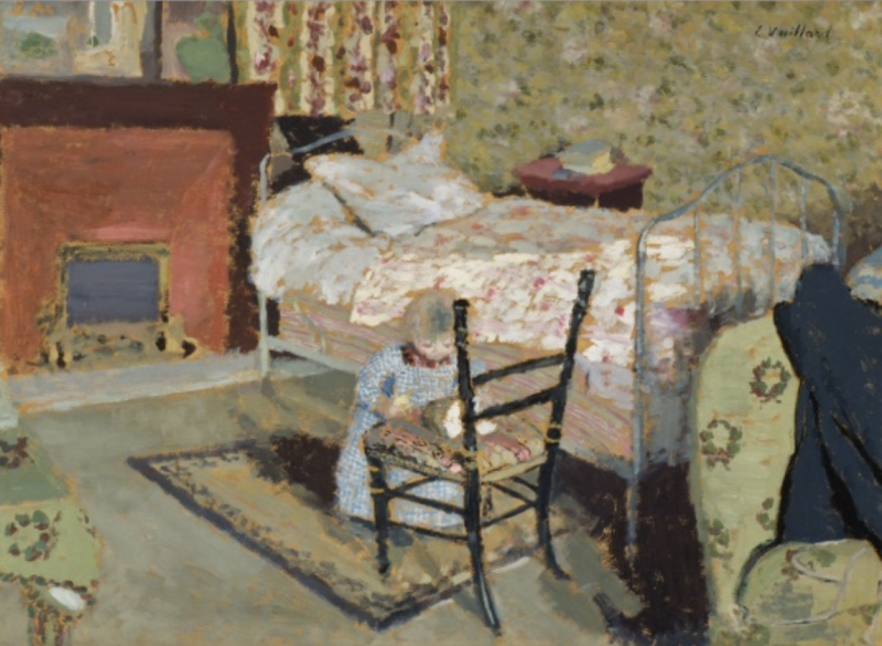 Ein Kind spielt vor einem Holzstuhl in einem Schlafzimmer mit einem Bett und einem Kamin im Hintergrund.