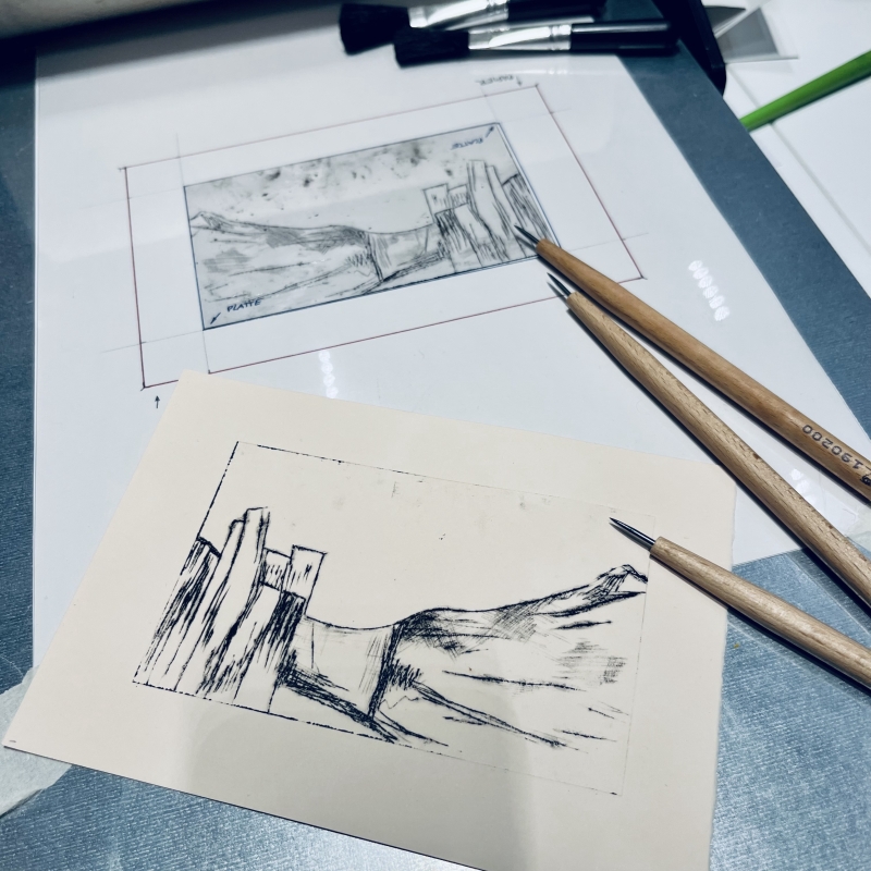 Skizze einer Landschaft mit Gebäuden, umgeben von Hügeln, auf einem Tisch mit Zeichenutensilien.