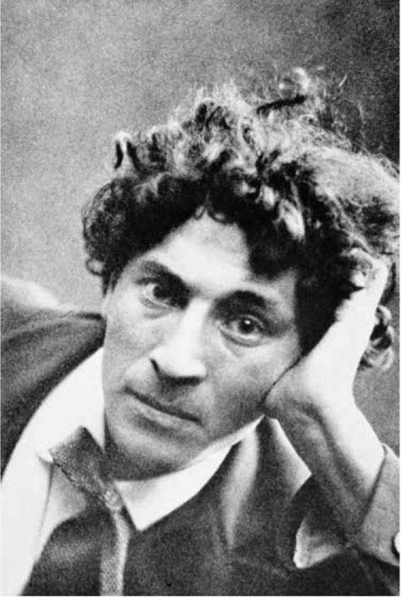 Black and white portrait of a man with curly hair, resting his head on his hand, gazing thoughtfully at the viewer.