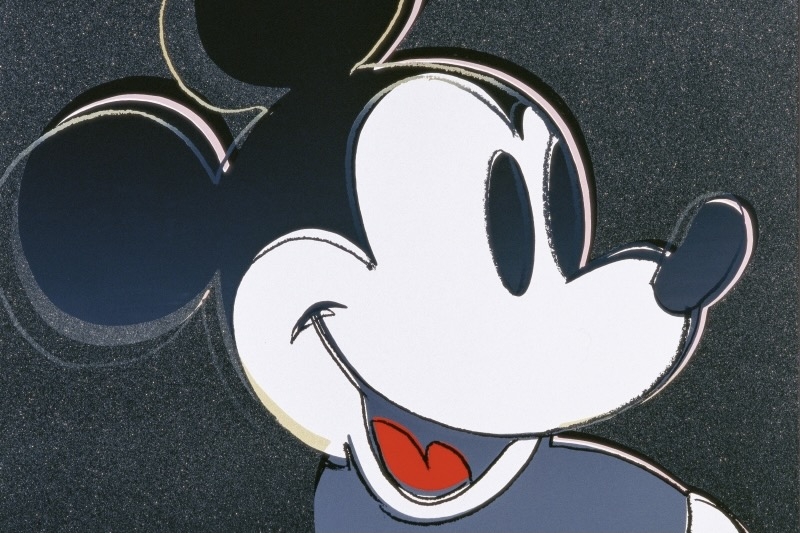 Mickey Mouse's smiling face with large ears, outlined in black, against a textured dark background.