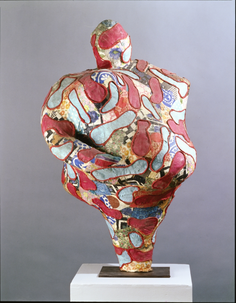 Abstrakte Skulptur in lebhaften Farben, mit geschwungenen Formen und Mustern, auf einem weißen Sockel präsentiert.