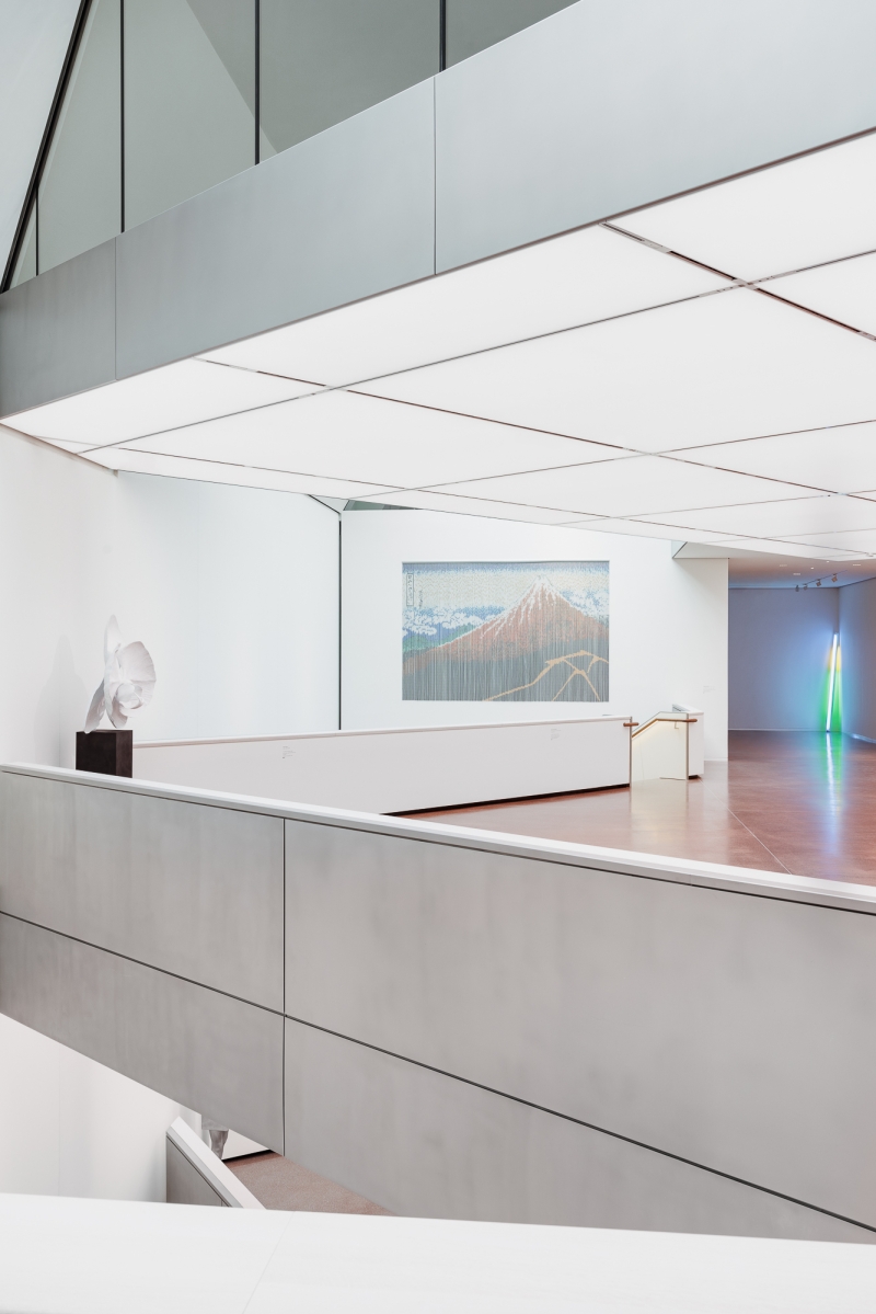Moderne Galerie mit minimalistischer Architektur, Skulptur links und Kunstwerk an der Wand im Hintergrund.