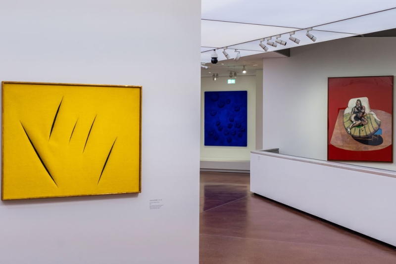 Yellow abstract artwork with sharp lines on the left, blue textured piece in the center, and red painting on the right.