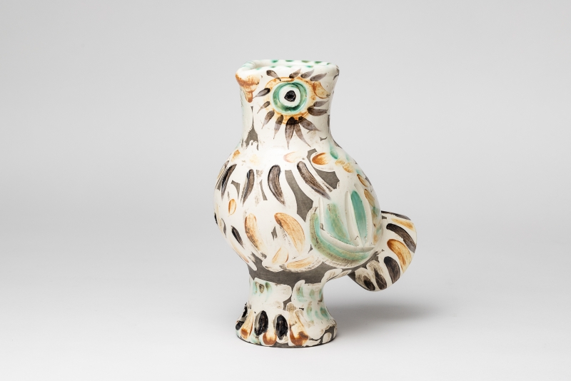 Ceramic vase shaped like a bird, featuring colorful patterns and a green rim, with a round body and a small tail.