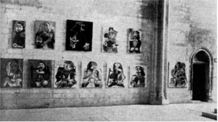 A gallery wall displays several abstract paintings by Picasso, with a doorway visible on the right side.