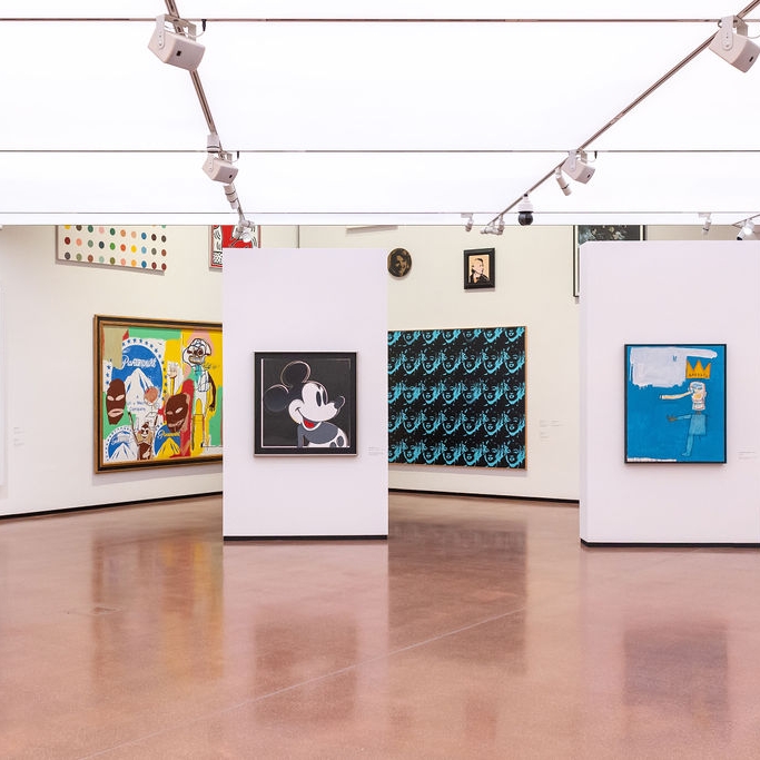 Moderne Galerie mit bunten Kunstwerken, weißen Wänden und einem glänzenden Boden.