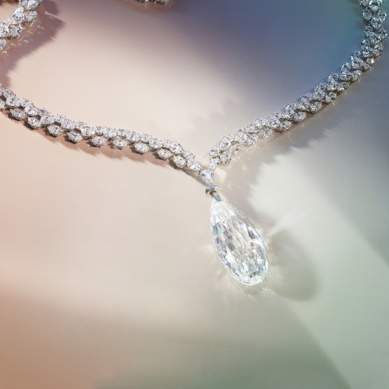Elegant diamond necklace with a teardrop pendant, featuring intricate sparkling links against a soft gradient background.