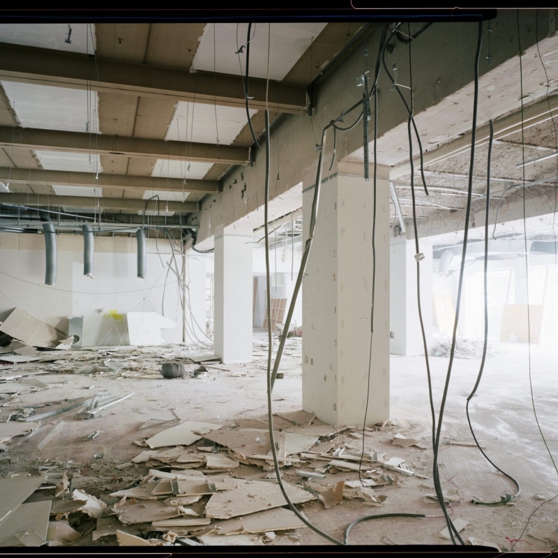 Construction site with debris, exposed wires, and unfinished walls, showcasing a chaotic and dusty environment.